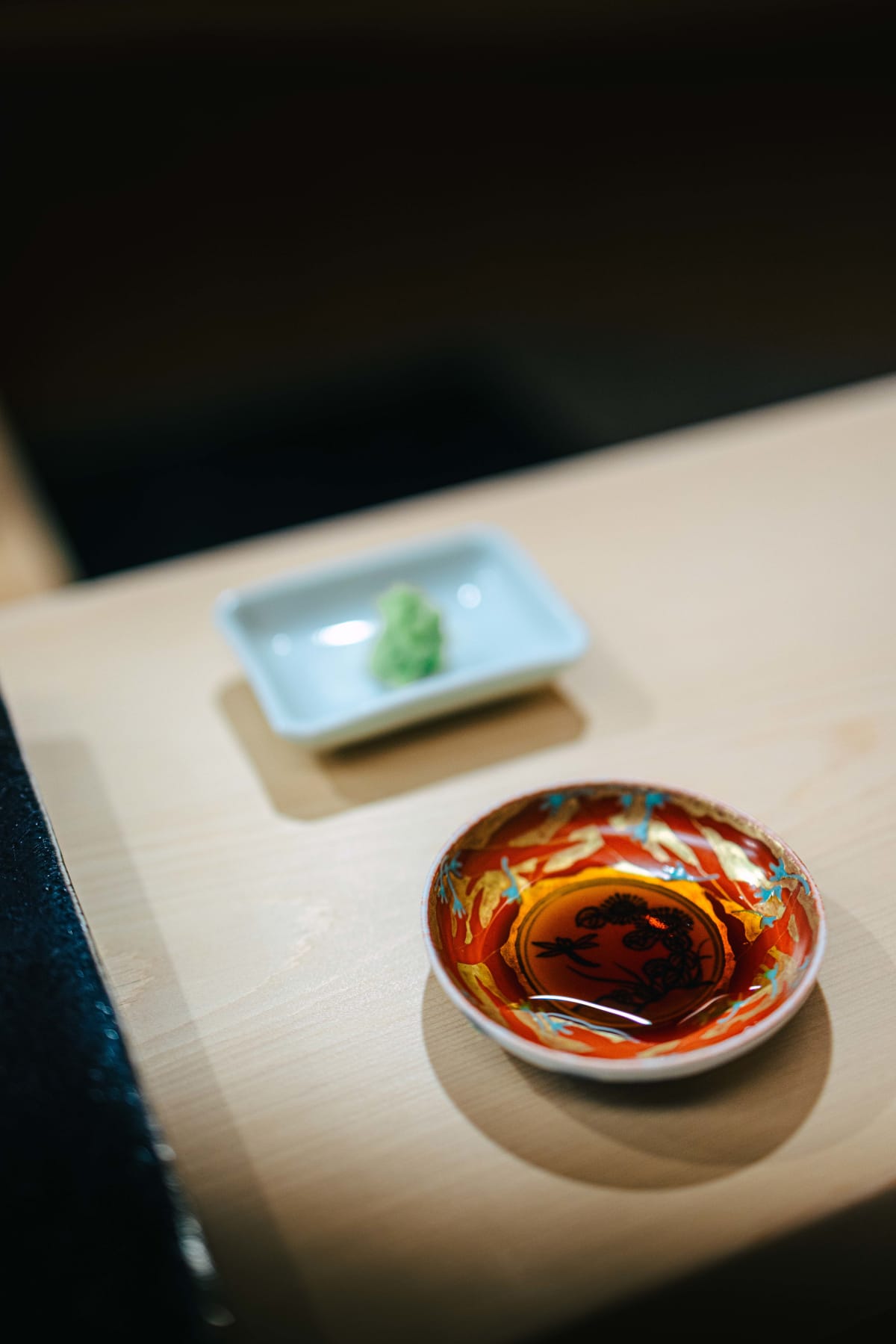 Nihonbashi Kakigaracho Sugita, Tokyo: fresh wasabi in a small white dish and soy sauce in a red and gold painted dish, set out for the tsumami
