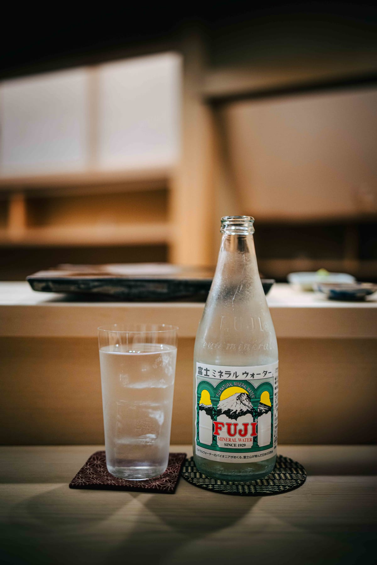 Nihonbashi Kakigaracho Sugita, Tokyo: a bottle of Fuji Mineral Water beside a glass of water on the counter