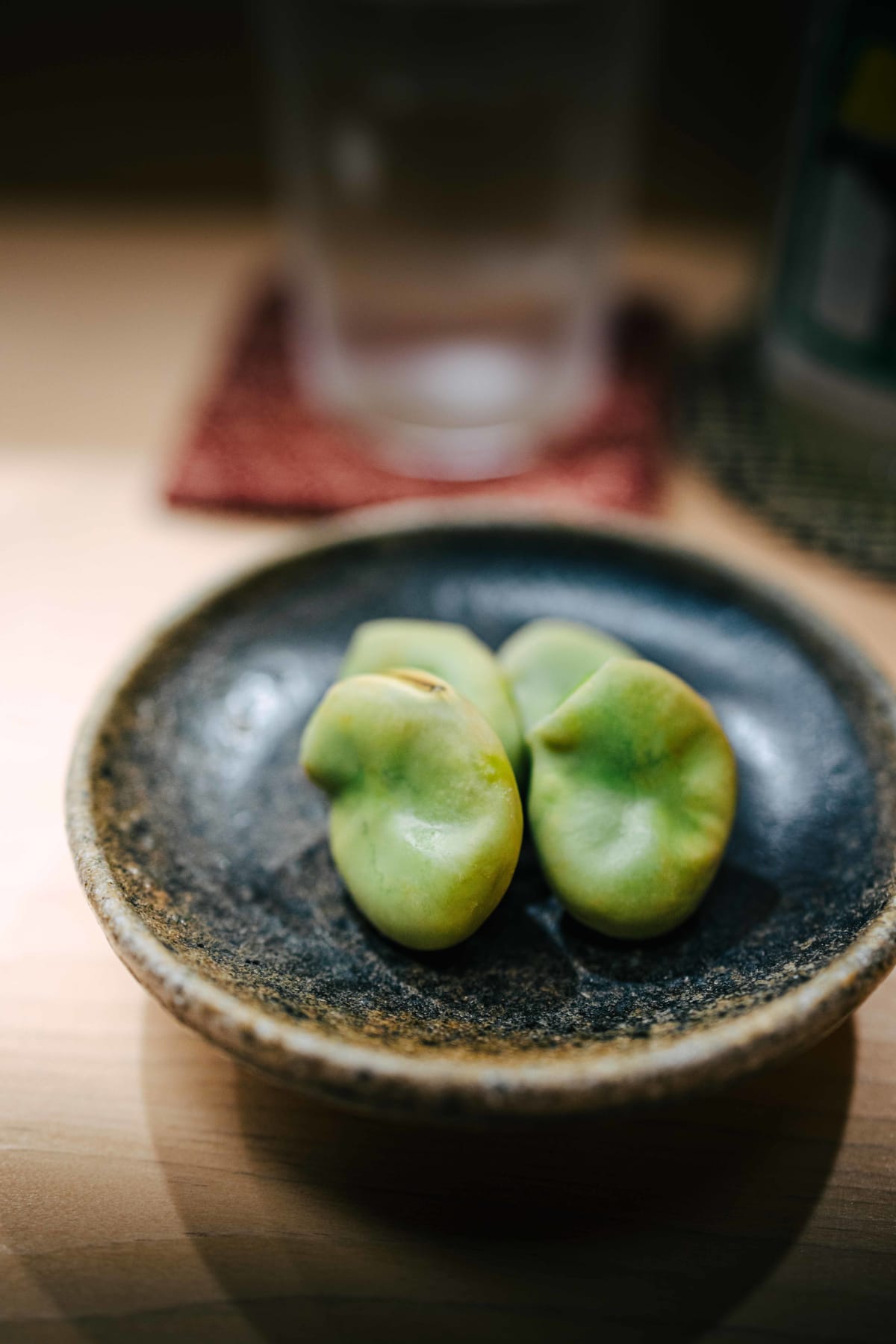 Nihonbashi Kakigaracho Sugita, Tokyo: sora mame, broad beans in their skins, on a dark speckled stoneware plate