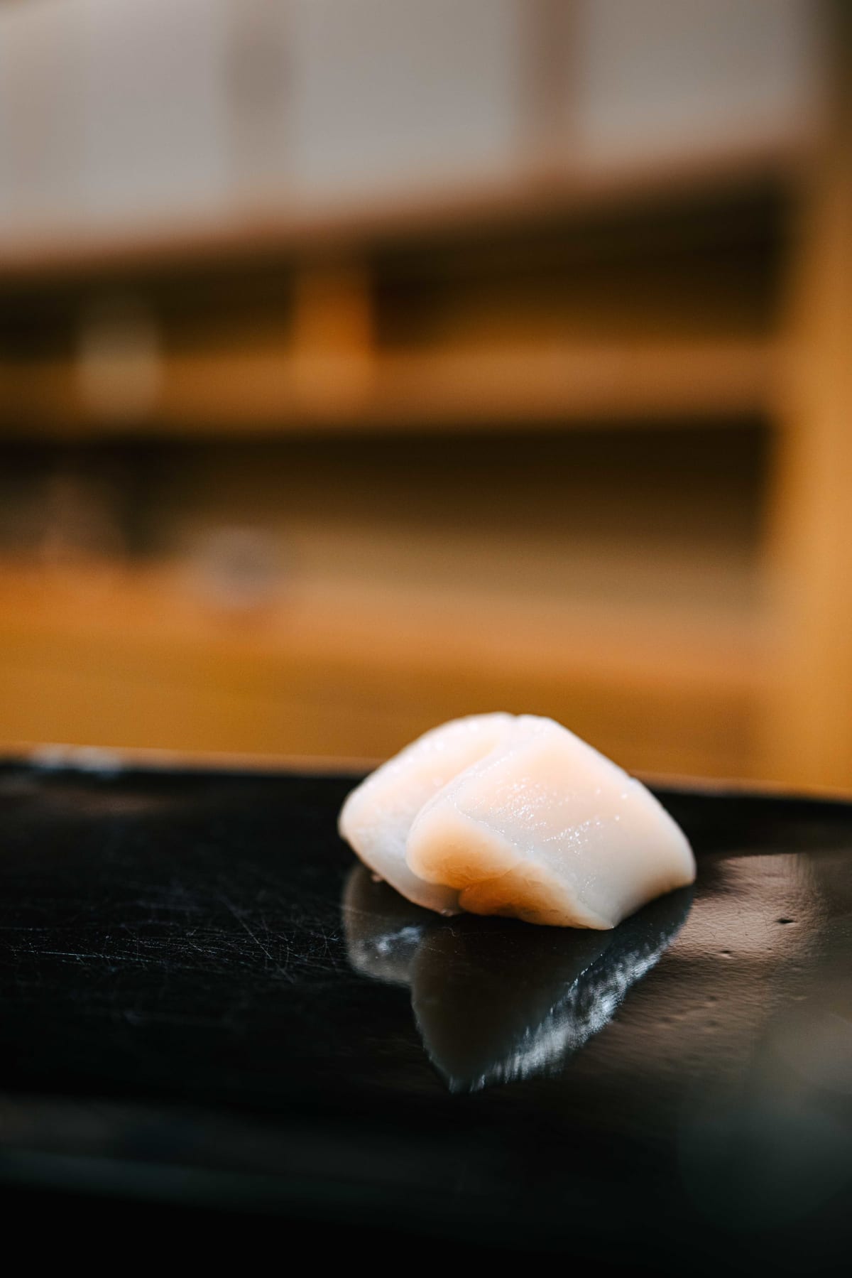 Nihonbashi Kakigaracho Sugita, Tokyo: hotate sashimi, two thick pieces of scallop on the black lacquer board, then one lifted with chopsticks