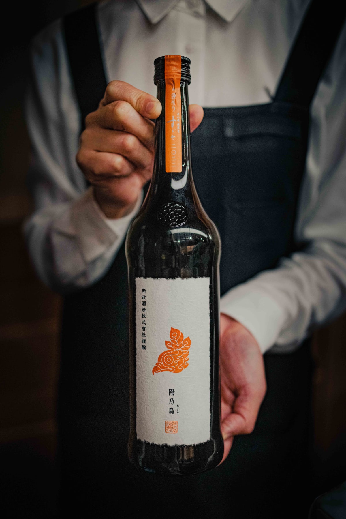 Nihonbashi Kakigaracho Sugita, Tokyo: a member of staff holding up the bottle of Aramasa Hinotori, orange tape around its neck
