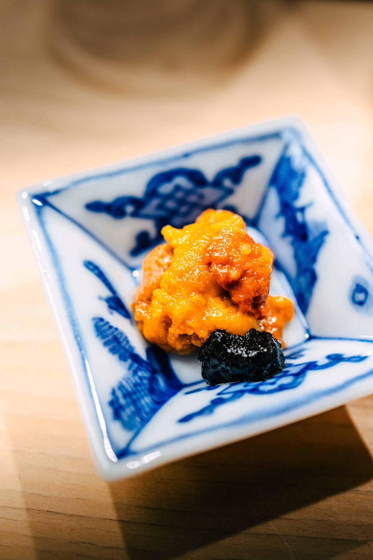 Nihonbashi Kakigaracho Sugita, Tokyo: the uni, dense and glossy, beside a dab of dark relish in a square blue and white dish