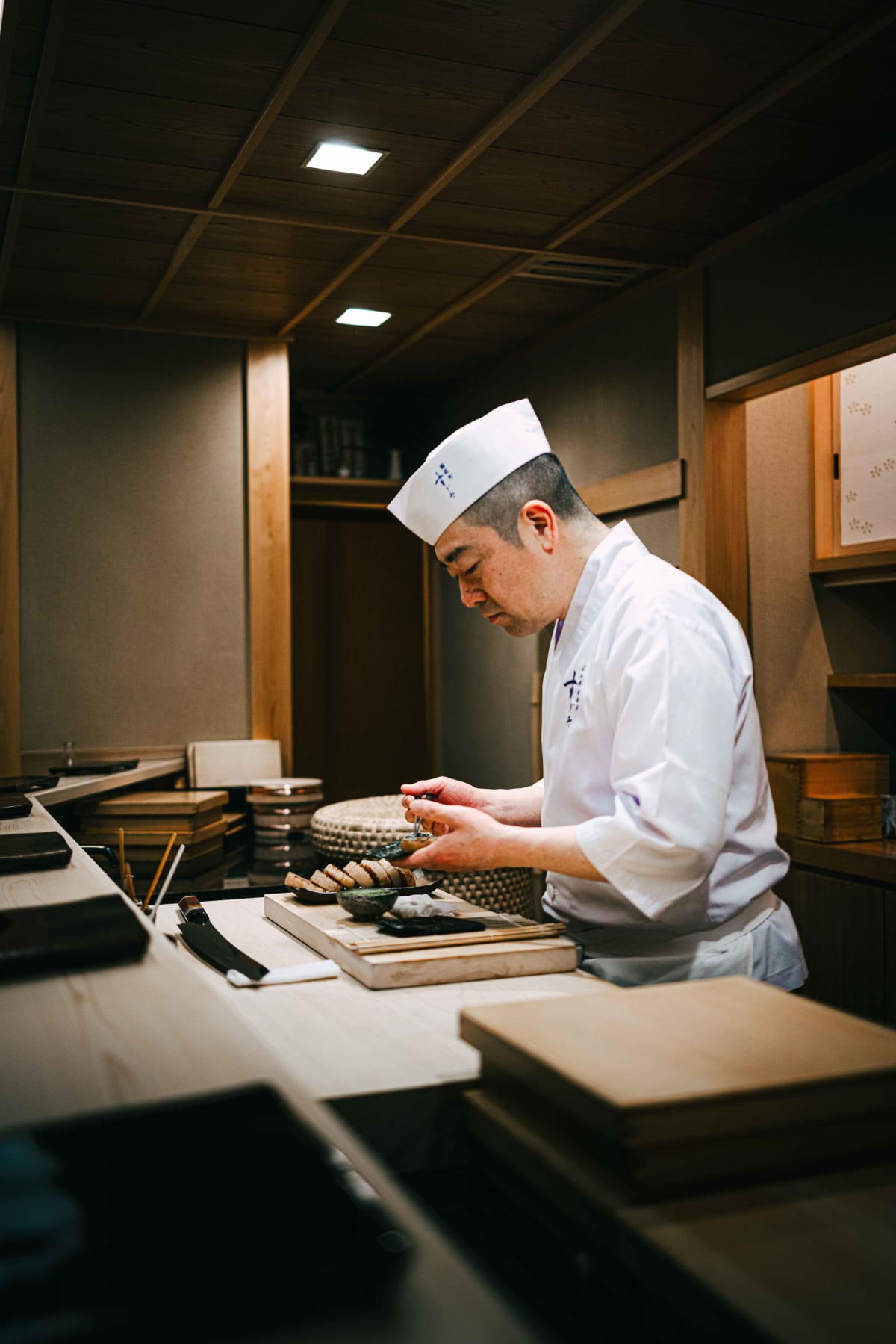 Nihonbashi Kakigaracho Sugita, Tokyo: Sugita at the counter preparing the isobeyaki, slices of grilled scallop lined up on the board