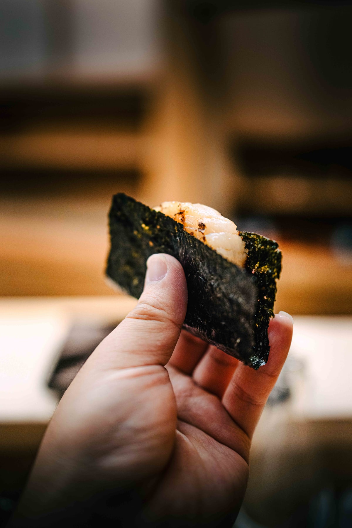 Nihonbashi Kakigaracho Sugita, Tokyo: the isobeyaki in hand, a thick piece of grilled scallop wrapped in nori