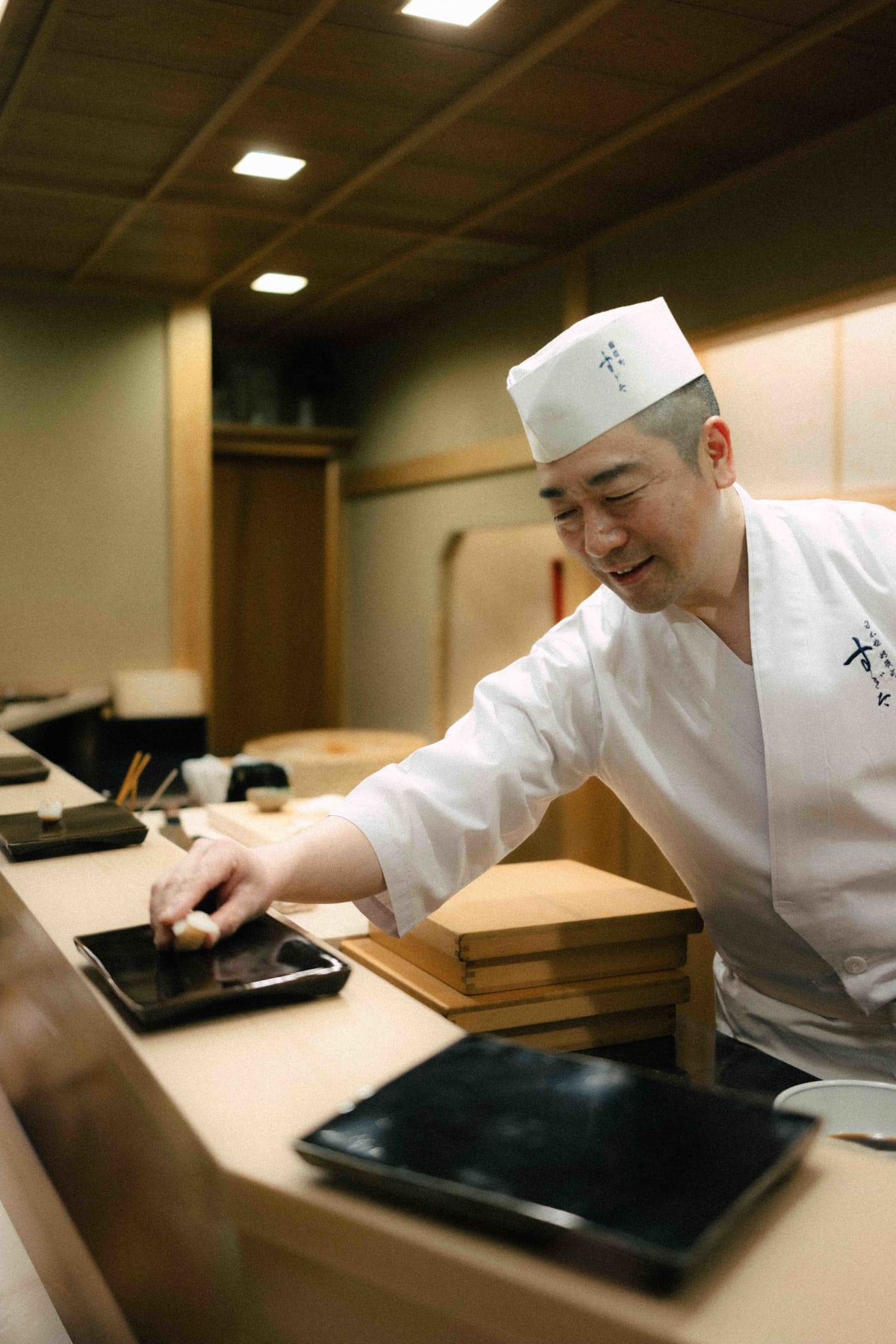Nihonbashi Kakigaracho Sugita, Tokyo: Sugita smiling at the counter as he sets down a piece of nigiri for a guest
