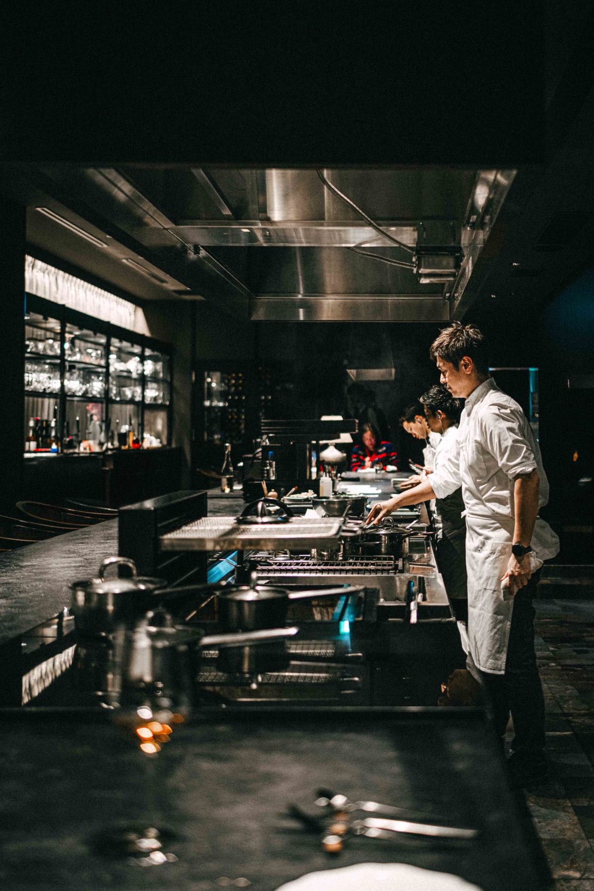 Florilège, Tokyo: chefs in white at the stoves of the open kitchen, glassware shelved along the back wall
