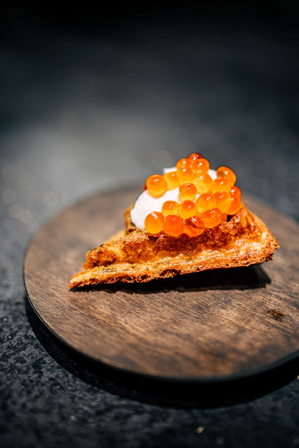 Florilège, Tokyo: the butterbur waffle topped with sour cream and a heap of glistening salmon roe, on a dark wooden board