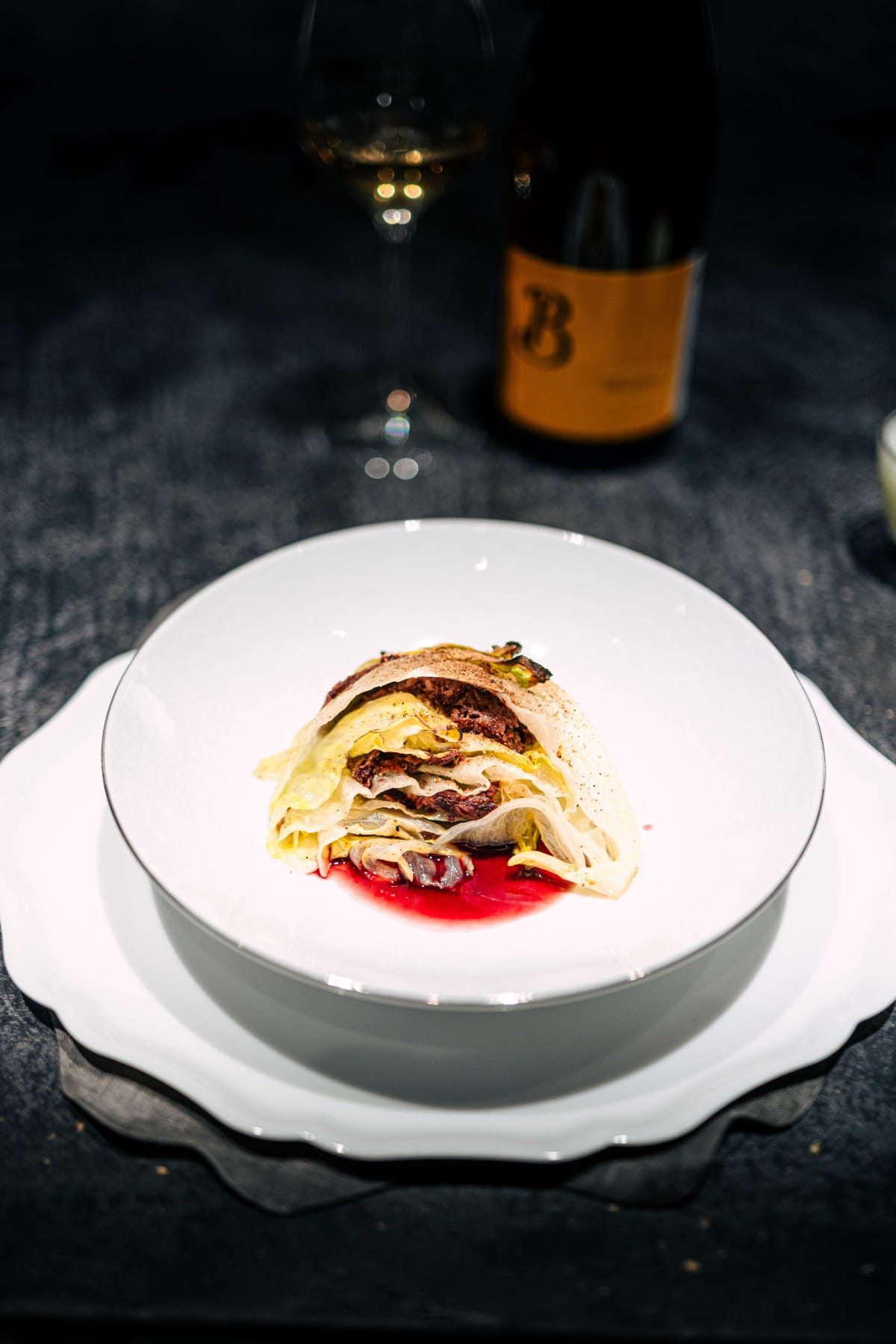 Florilège, Tokyo: lettuce layered with dark XO sauce over a pool of red treviso sauce, the Pilorget bottle behind