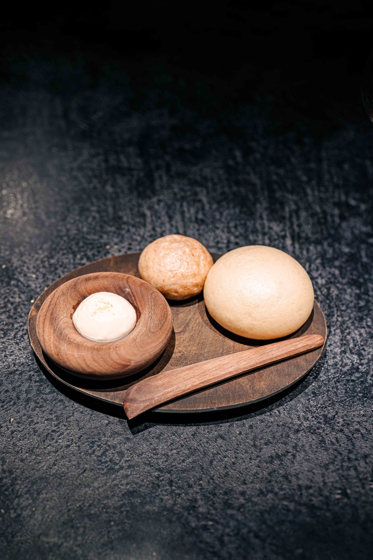 Florilège, Tokyo: two round breads on a wooden plate with a bowl of cream cheese-like spread and a wooden knife