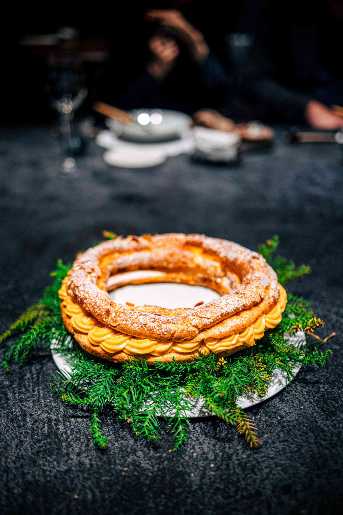 Florilège, Tokyo: the whole ring of choux, dusted with sugar and almonds, shown on a bed of evergreen sprigs
