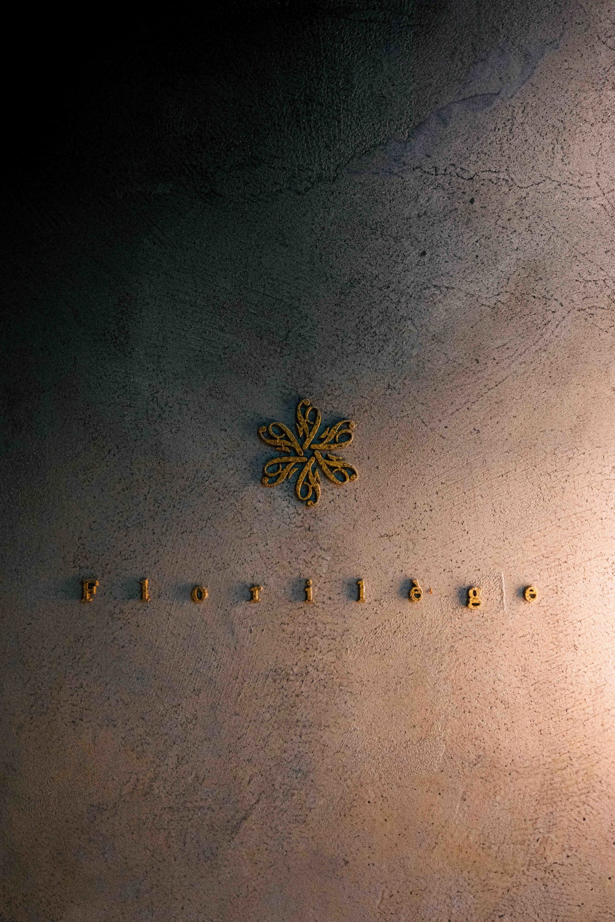 Florilège, Tokyo: the gold emblem and the name Florilège set into a textured plaster wall