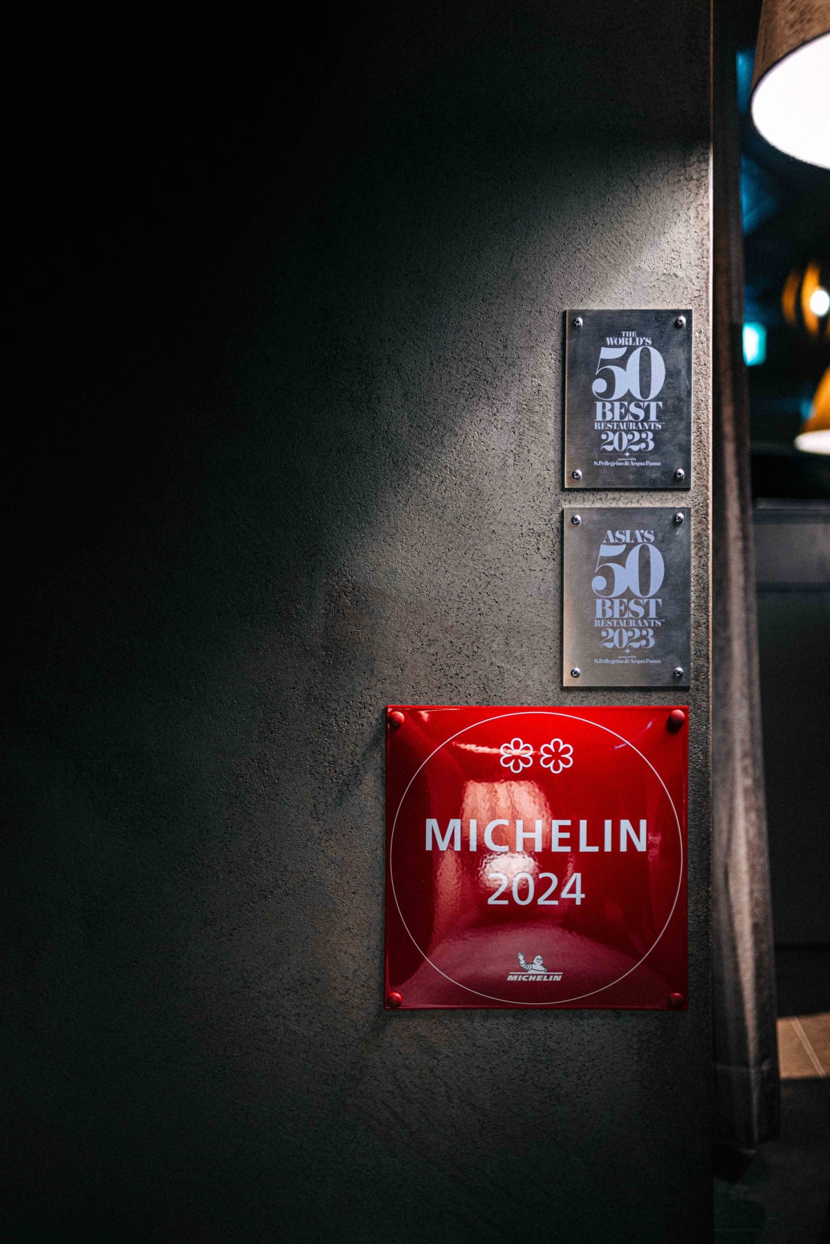 Florilège, Tokyo: the MICHELIN 2024 two-star plaque beneath The World's 50 Best and Asia's 50 Best 2023 plaques on the lobby wall