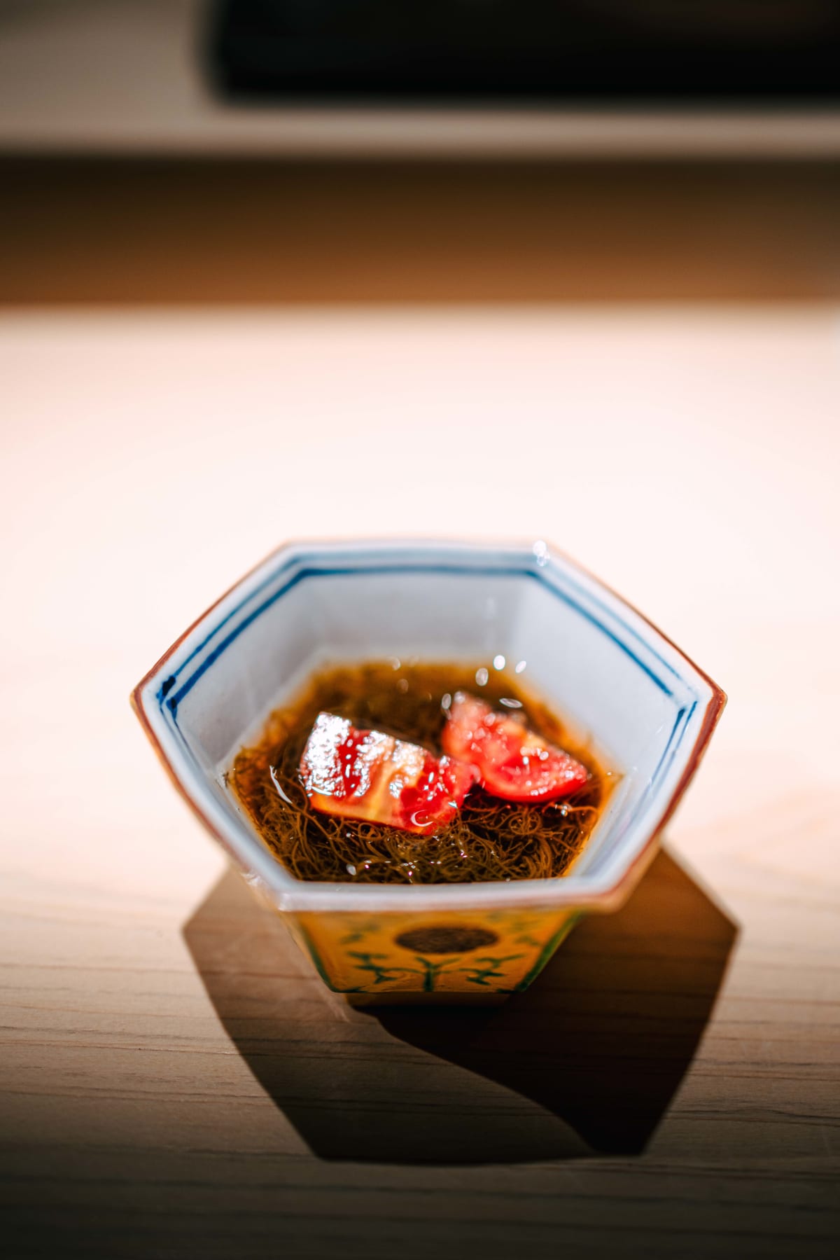 Sushi Juyon by Saito, Seoul: mozuku in a blue-rimmed hexagonal dish with two slices of tomato and a clear vinegar dressing