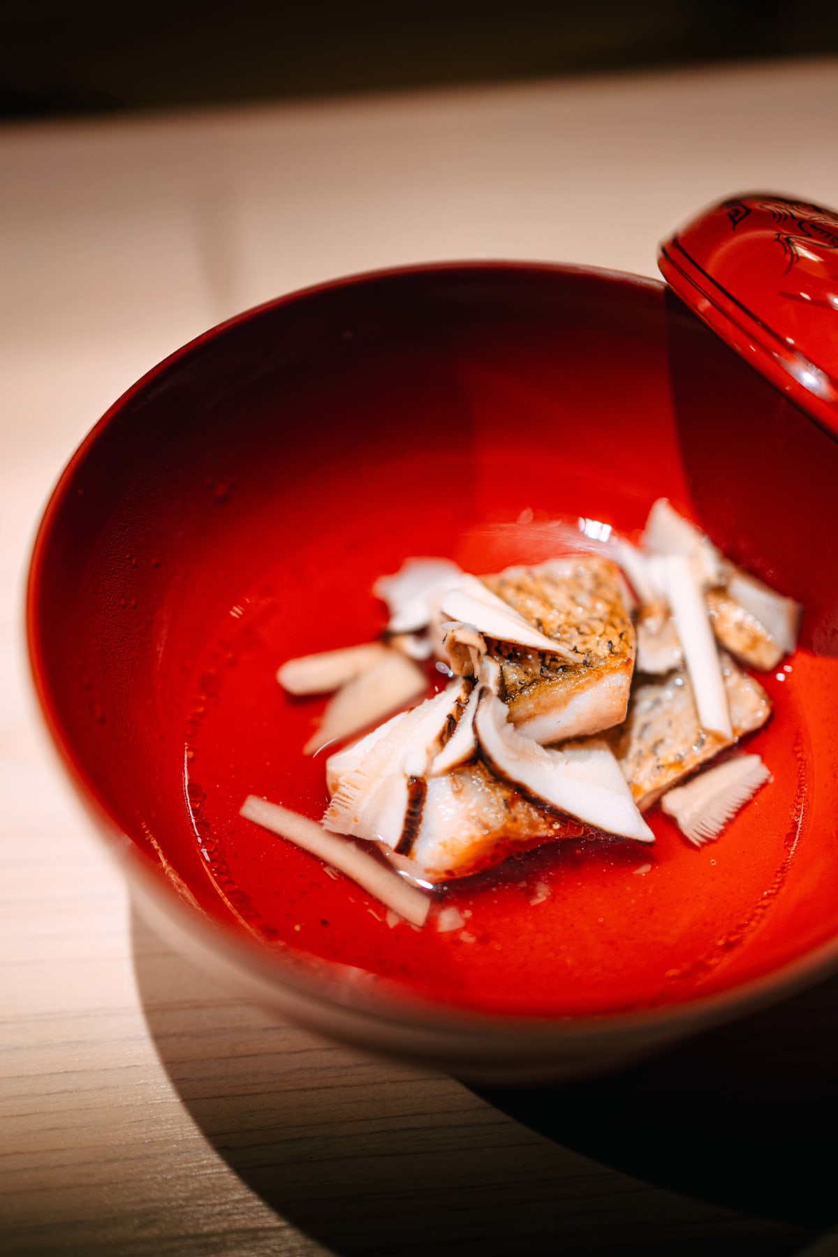 Sushi Juyon by Saito, Seoul: the nodoguro suimono in a red lacquered bowl with slices of matsutake, from two angles, then the second visit's suimono, a white fish with pink skin and grilled matsutake, in the same red bowl