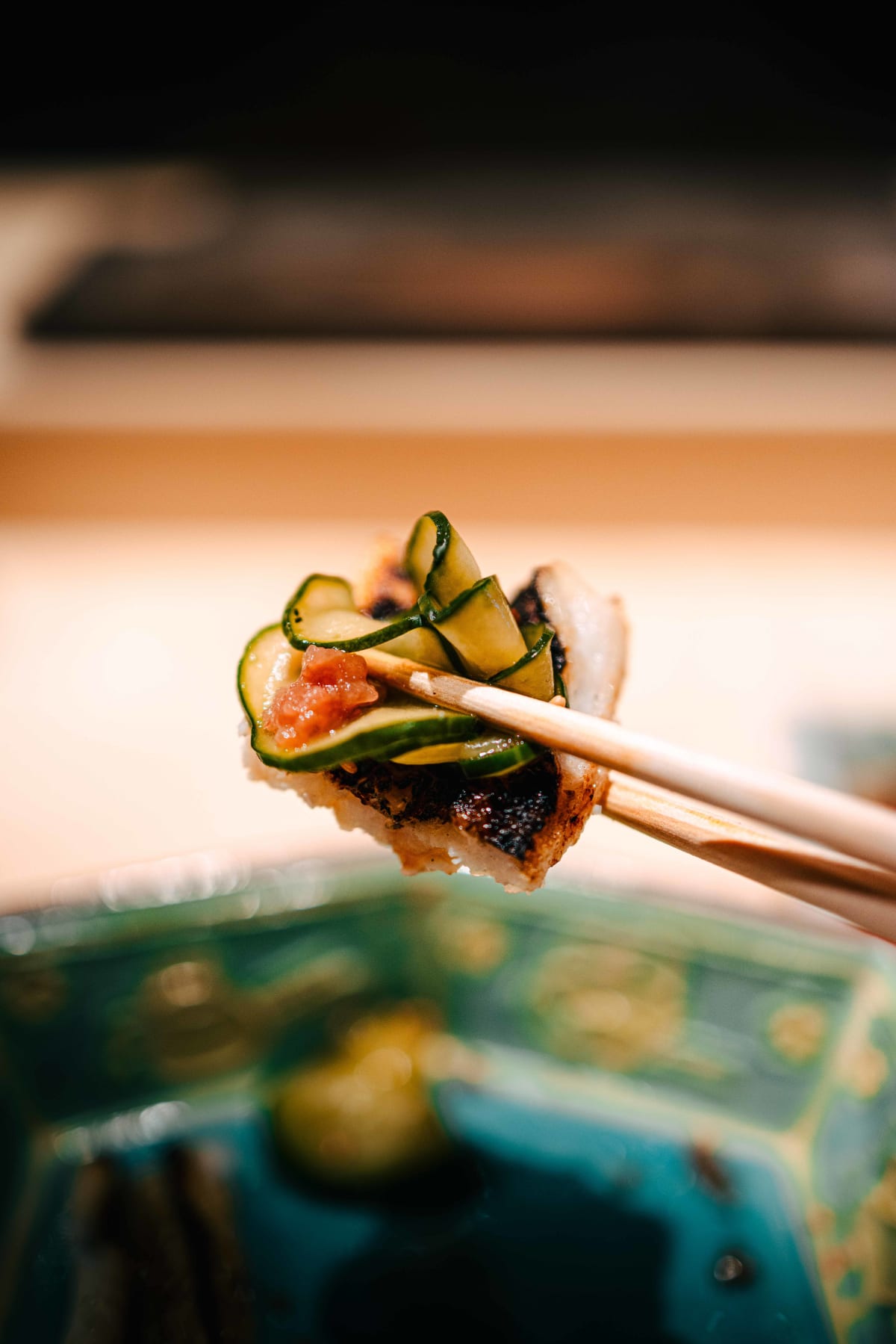 Sushi Juyon by Saito, Seoul: a piece of anago topped with cucumber and umeboshi, lifted on chopsticks