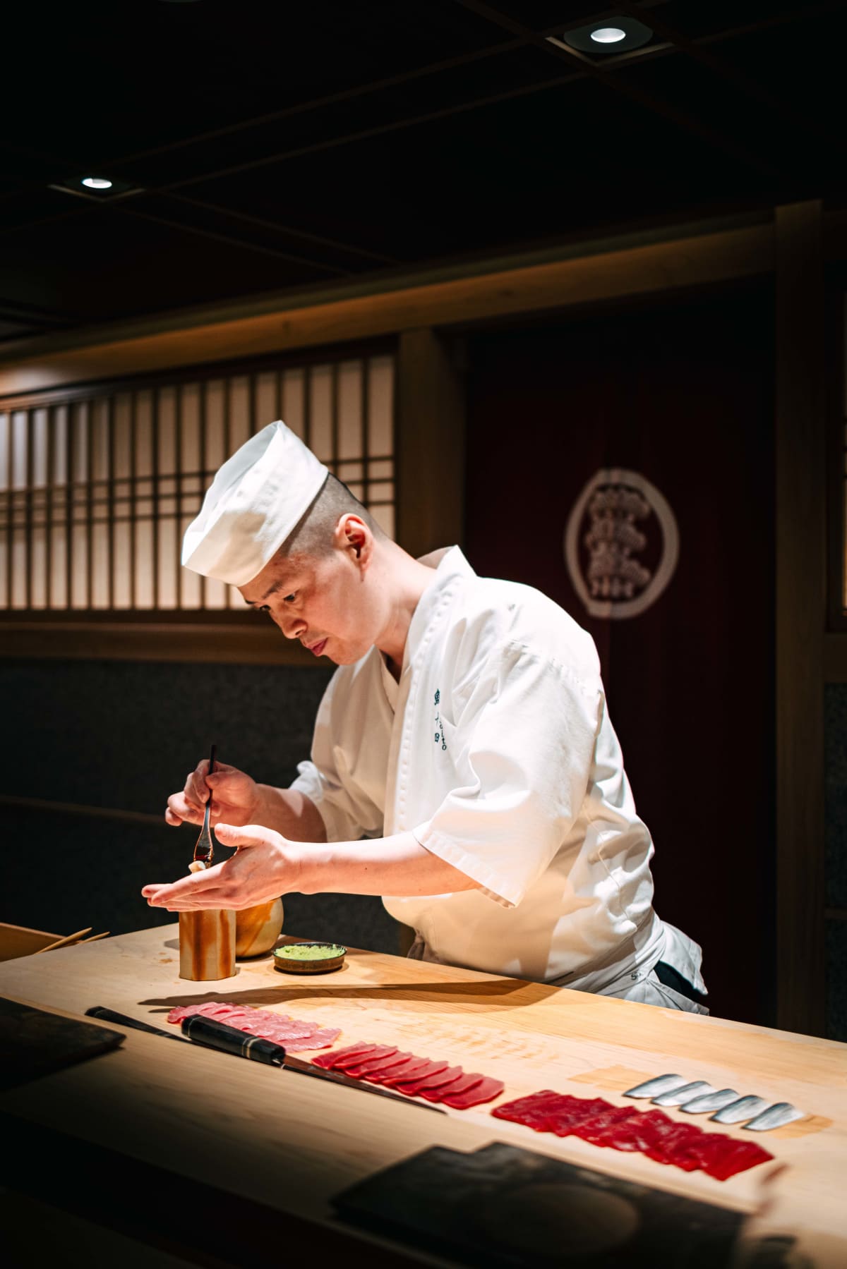 Sushi Juyon by Saito, Seoul: Kim Joo-young brushing on nikiri in front of the neta laid out in a row, then forming nigiri, and the row being set out on the second visit