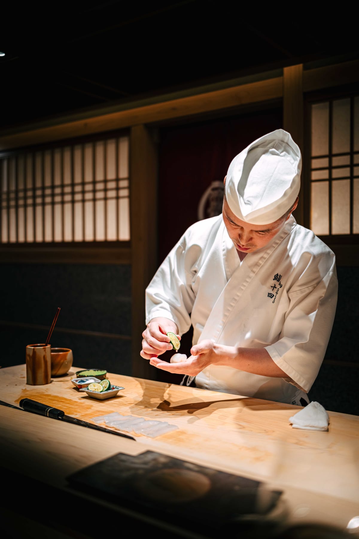 Sushi Juyon by Saito, Seoul: the taisho squeezing green citrus over hanchi at the counter
