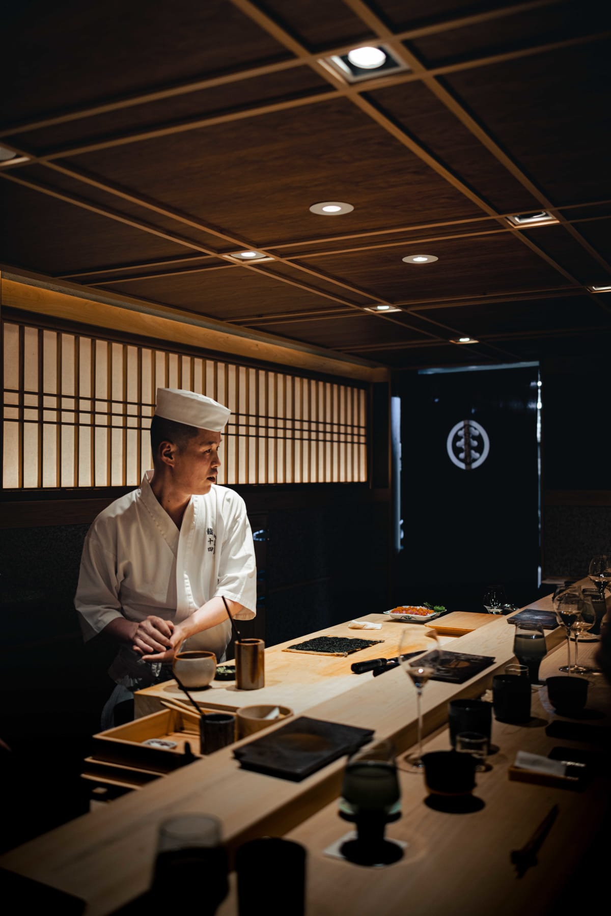 Sushi Juyon by Saito, Seoul: on the second visit, a cook at the nori, the taisho spreading shari over it and laying on the tuna, then slicing the roll