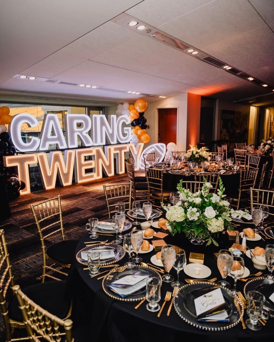 Caring Twenty light-up marquee letters with black and gold balloons at a Pittsburgh gala