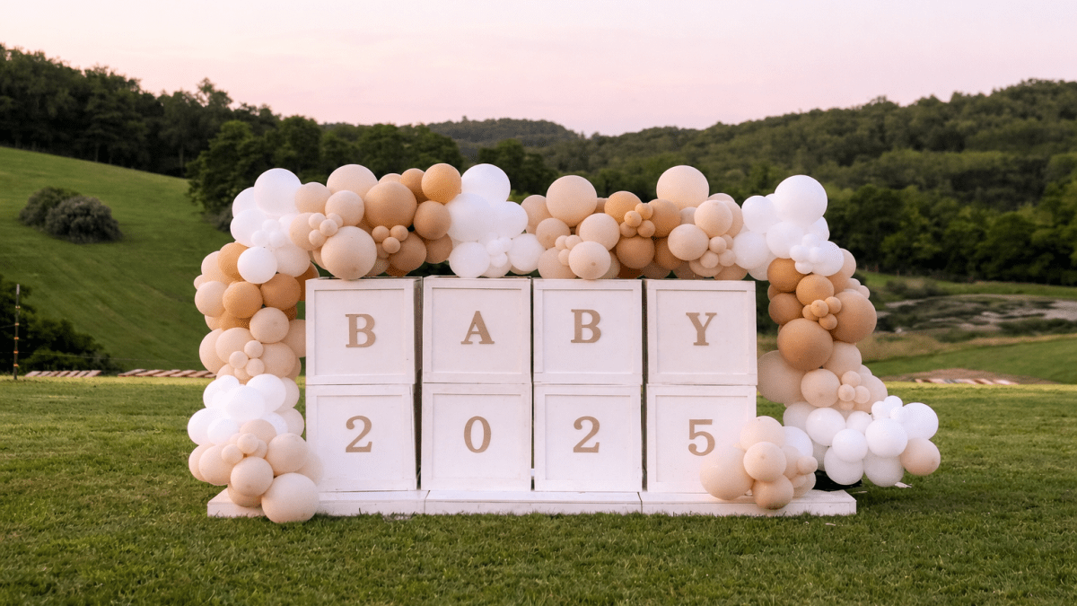 A lush organic balloon arch in blush, white, and gold installed at a Pittsburgh event venue by Party on Butler