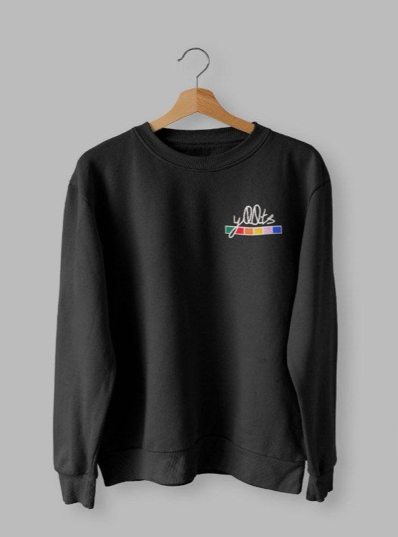 Front of tote bag with washed black canvas body, black straps, and tan leather handles and accents.