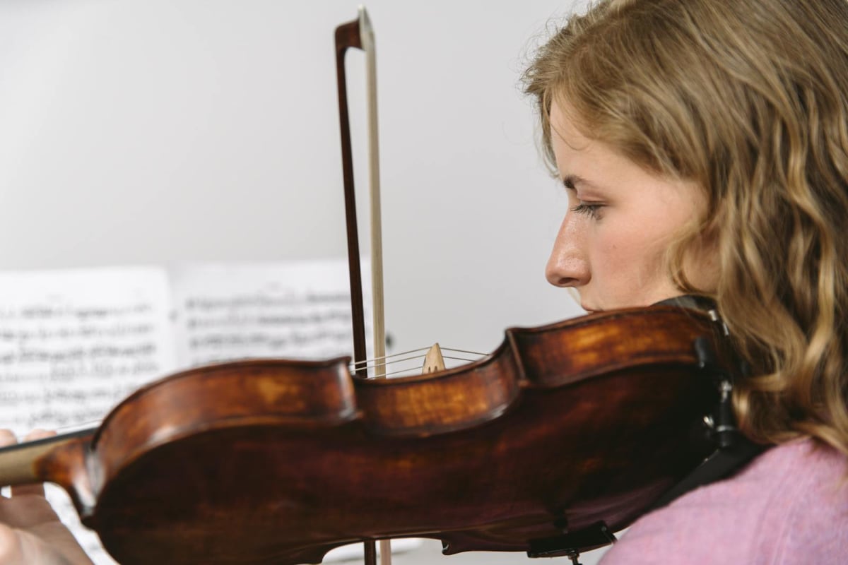 Young woman practicing violin with sheet music in the background