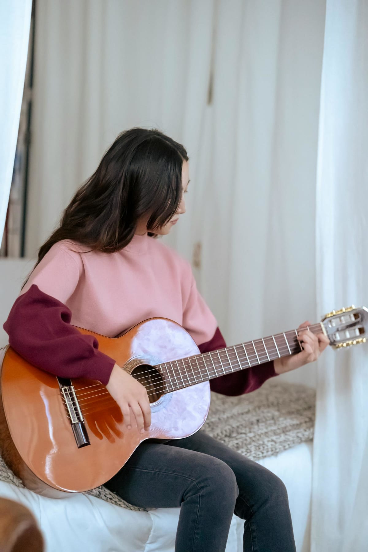 Person playing acoustic guitar at home during a quiet practice session
