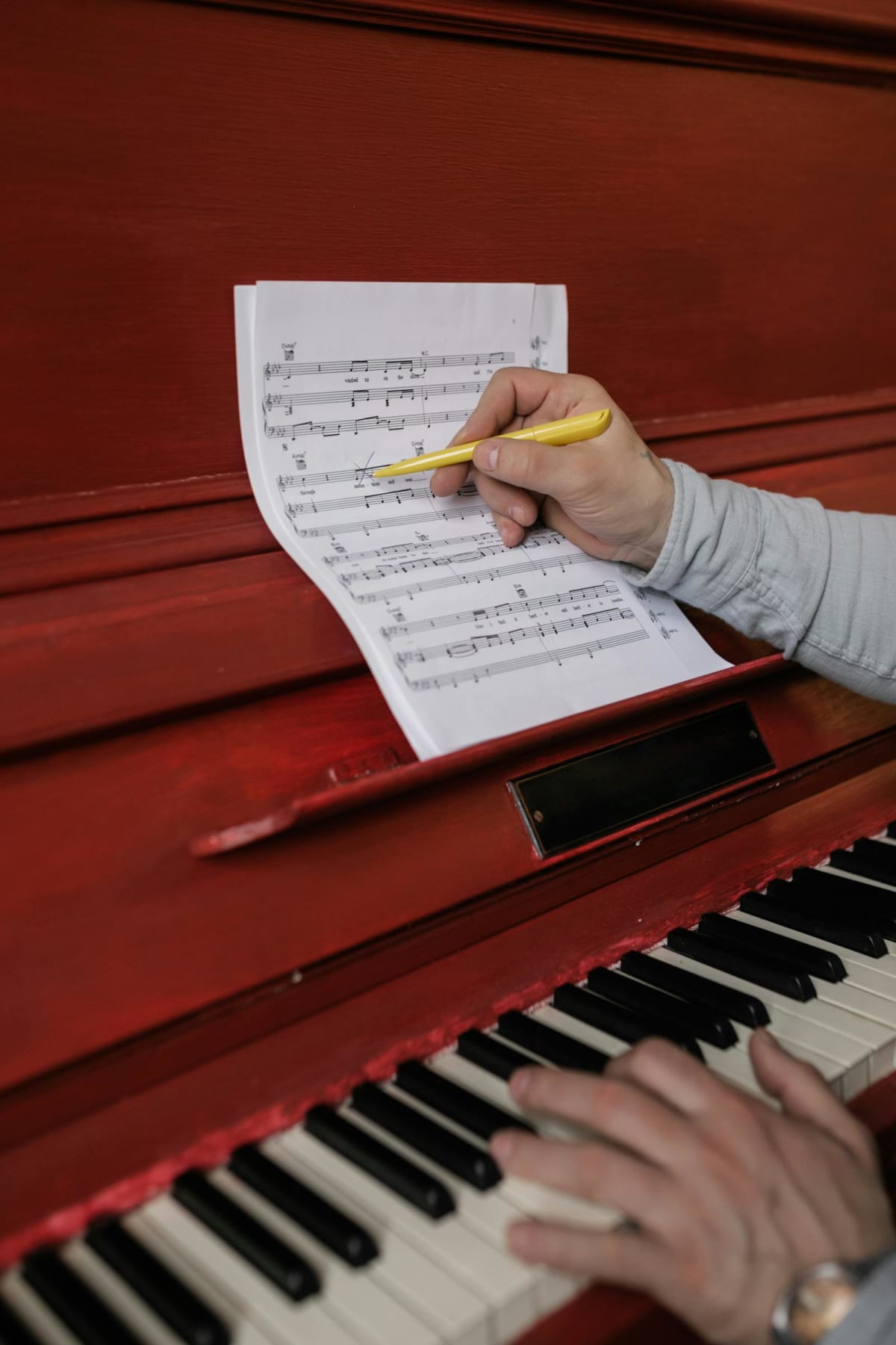 Person revising sheet music with a pencil on a piano