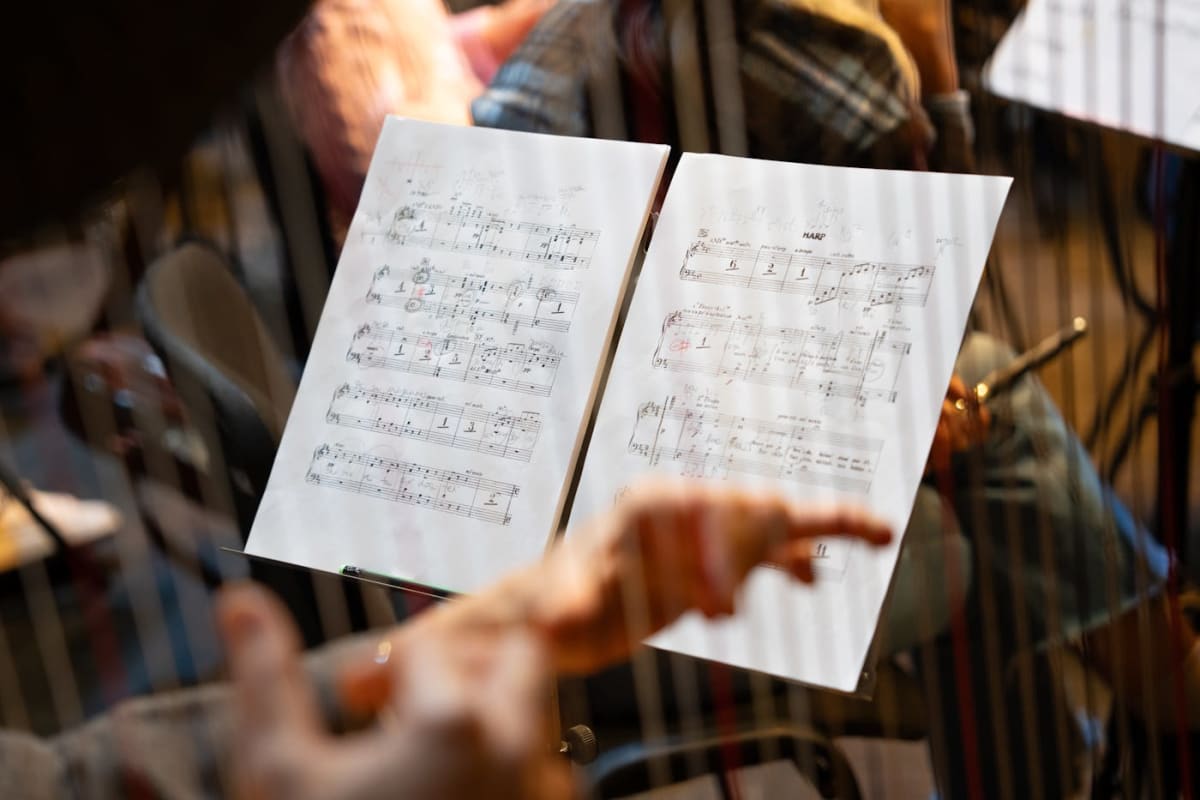 Close-up of sheet music with a musician’s hands nearby