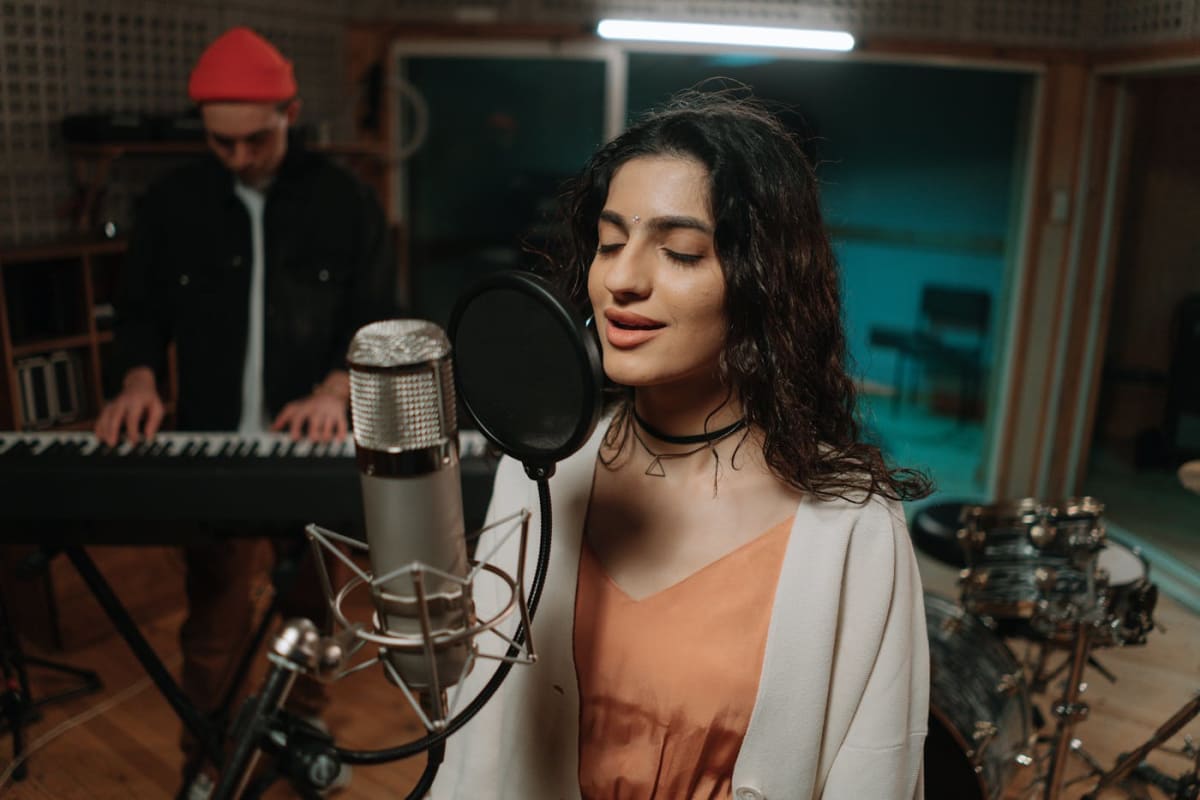 Singer rehearsing beside a keyboard in a studio