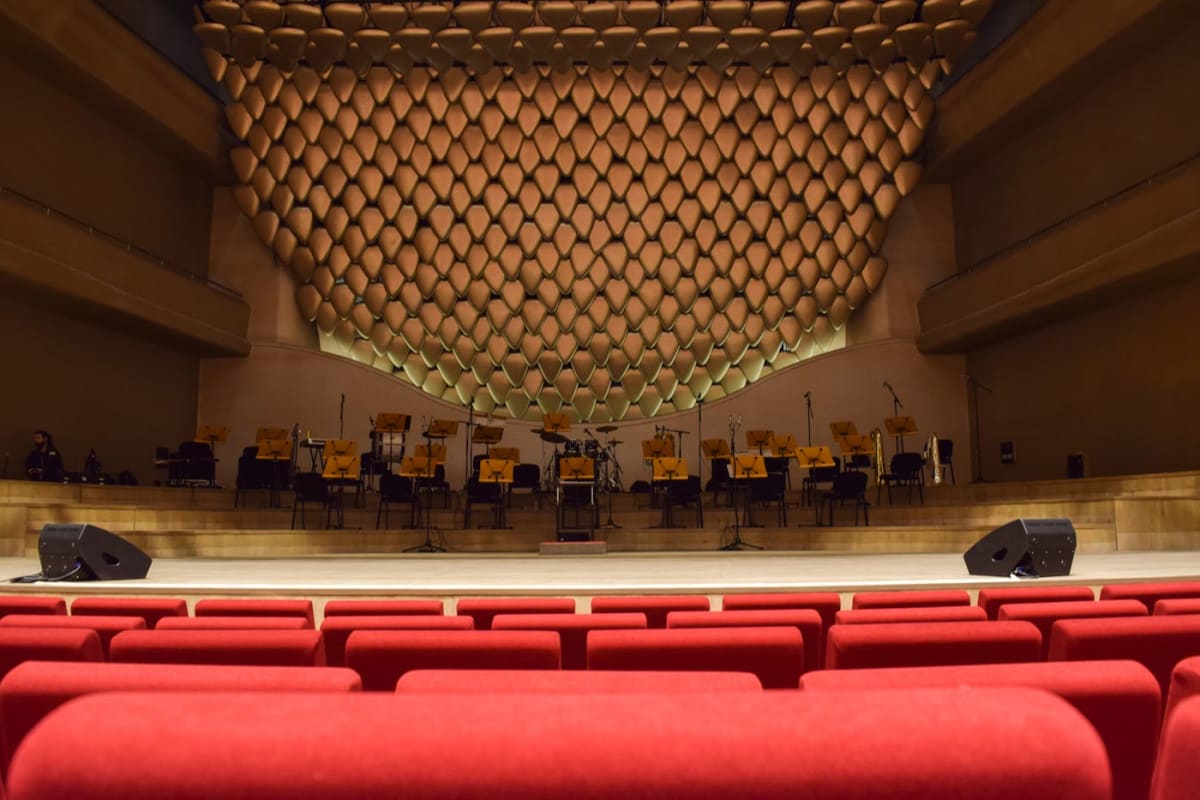 Empty concert hall with red seats and an unoccupied stage