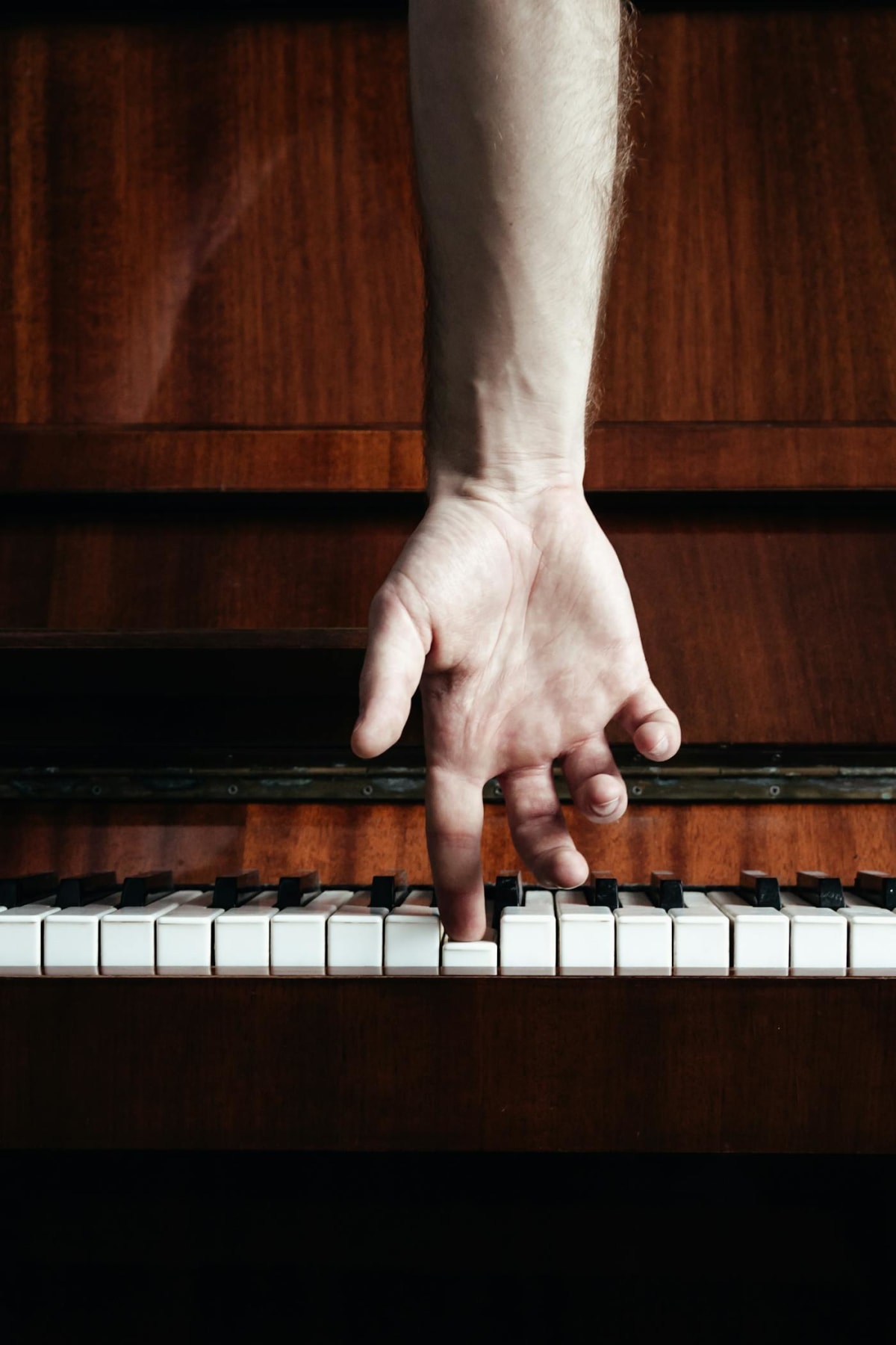 Close-up of a hand pressing one piano key during focused practice