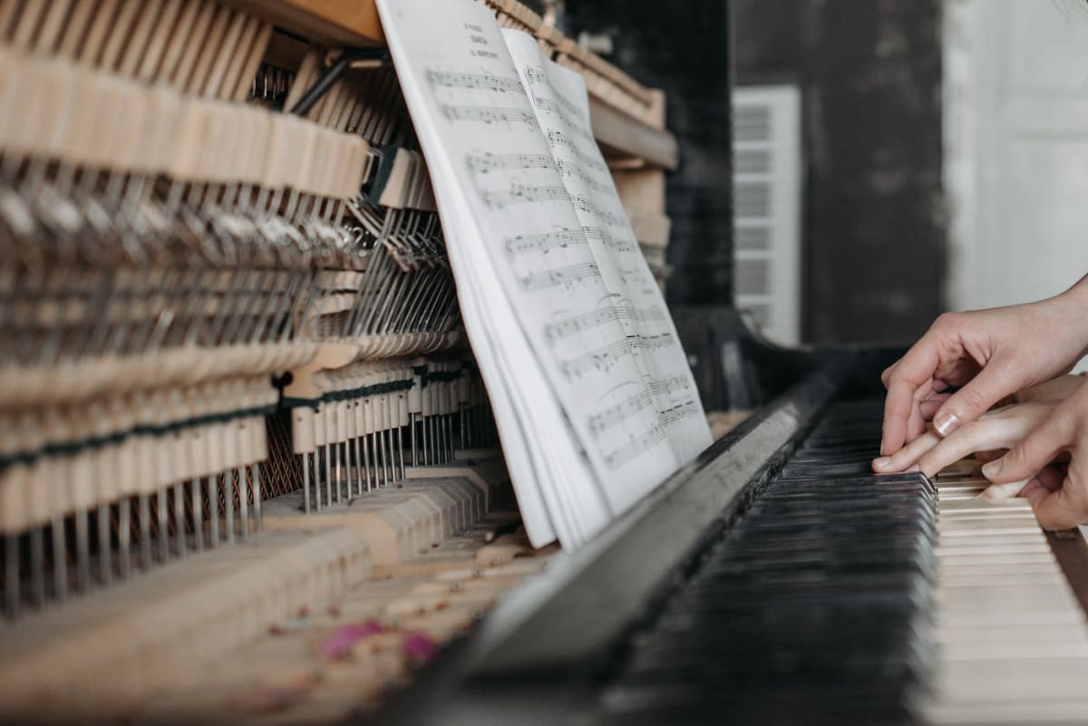 Close-up of hands playing piano keys with sheet music open