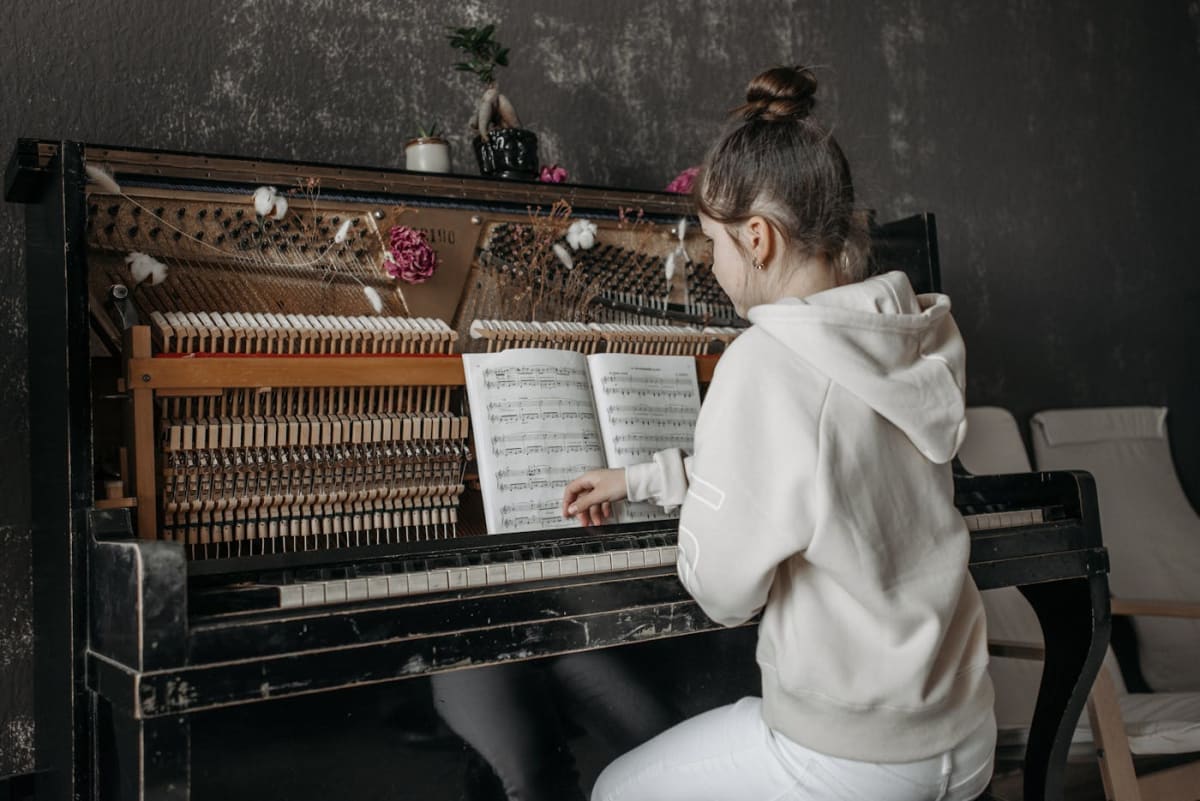 Close-up of an adult practicing piano with written music nearby