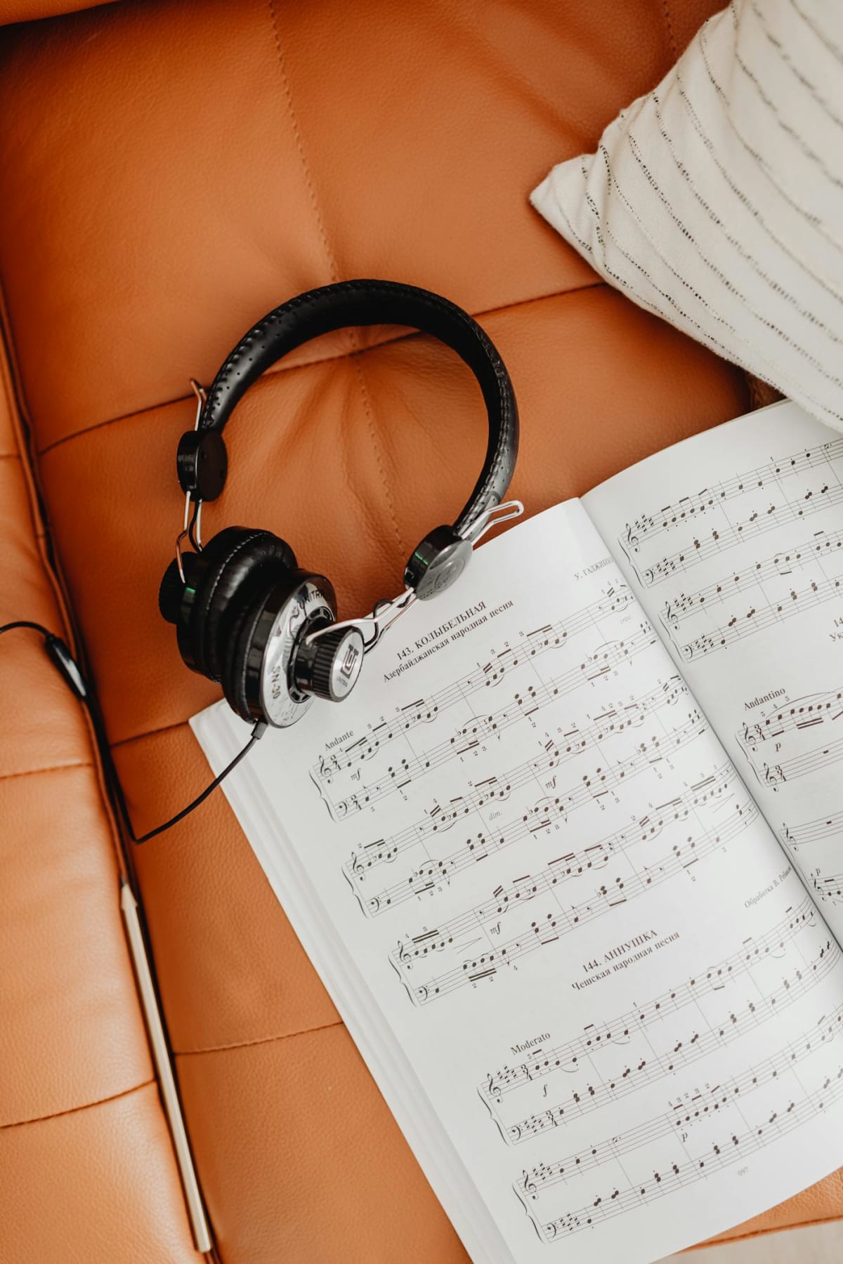 Headphones and a music sheet on a couch — the listening-back side of self-recording