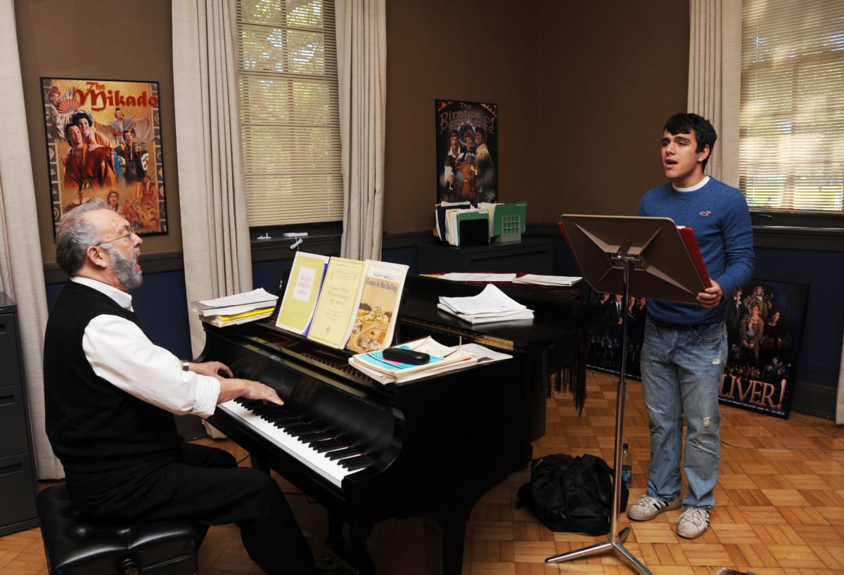 Private voice lesson with teacher, student, piano, and sheet music