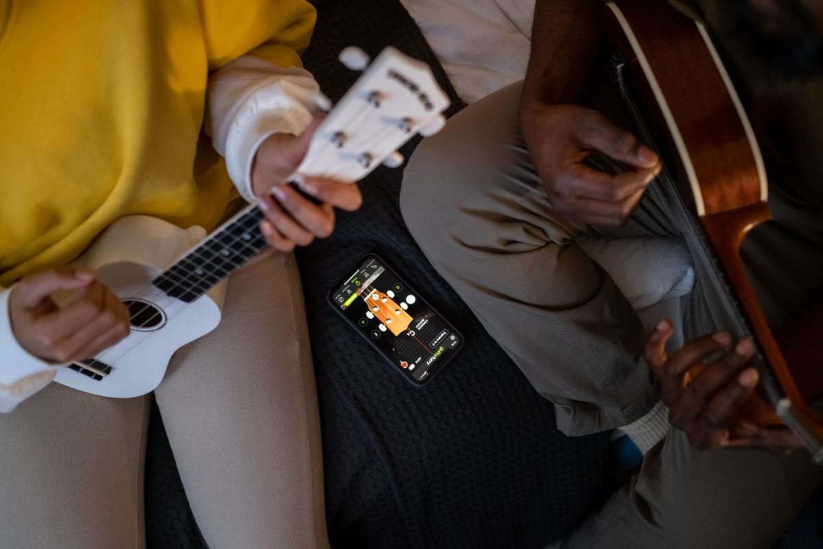 Two guitarists checking a practice app on a smartphone between exercises