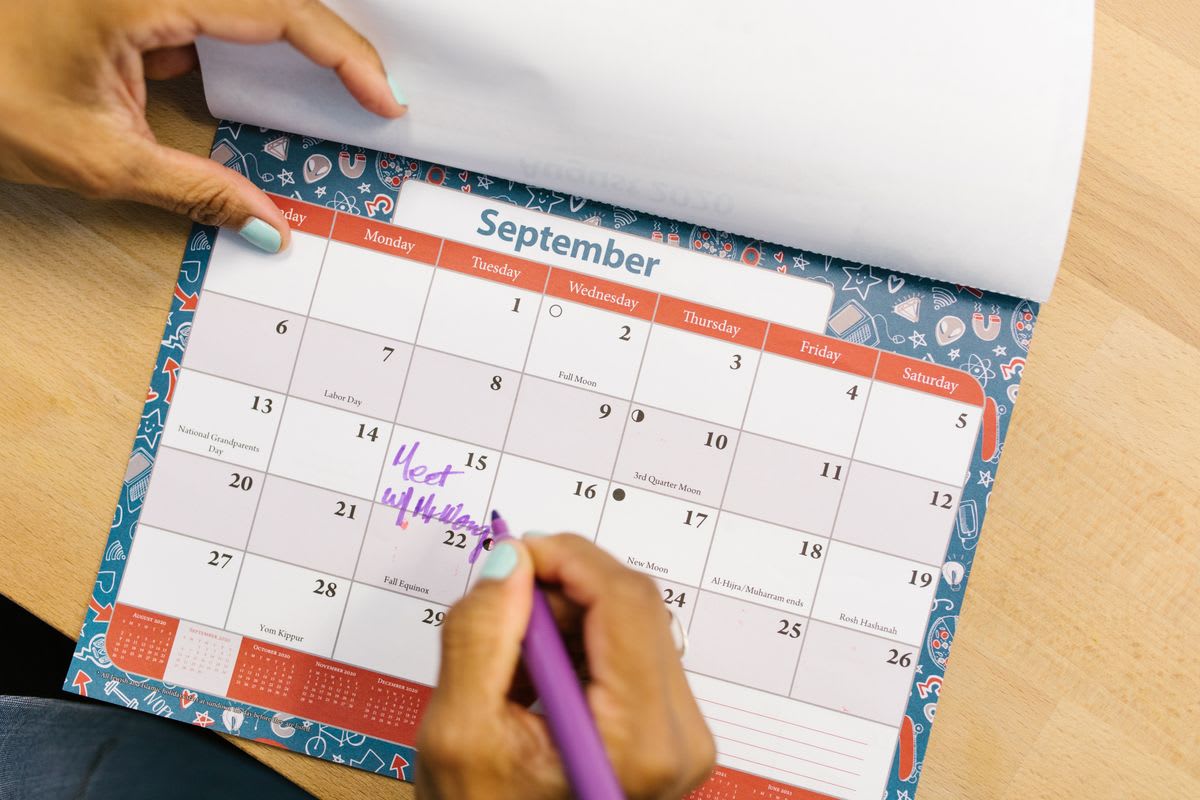 A person marking days on a calendar with a pen