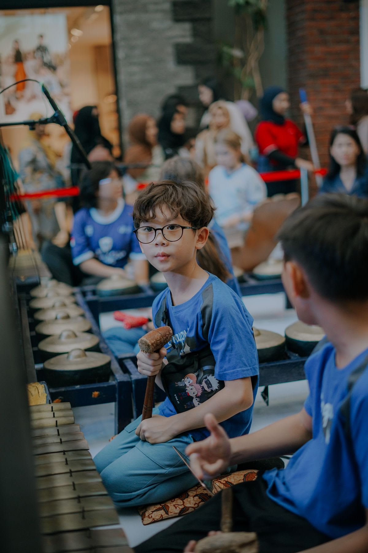 A young student in focus among many players during a group instrument class