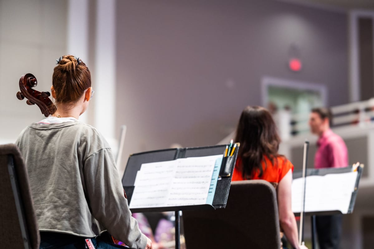 Students rehearsing with instruments and music stands in a conservatory ensemble room