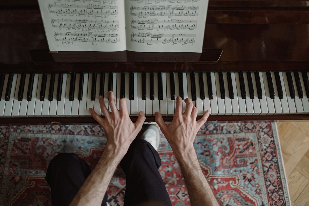 A pianist practising alone at an upright piano with the score open