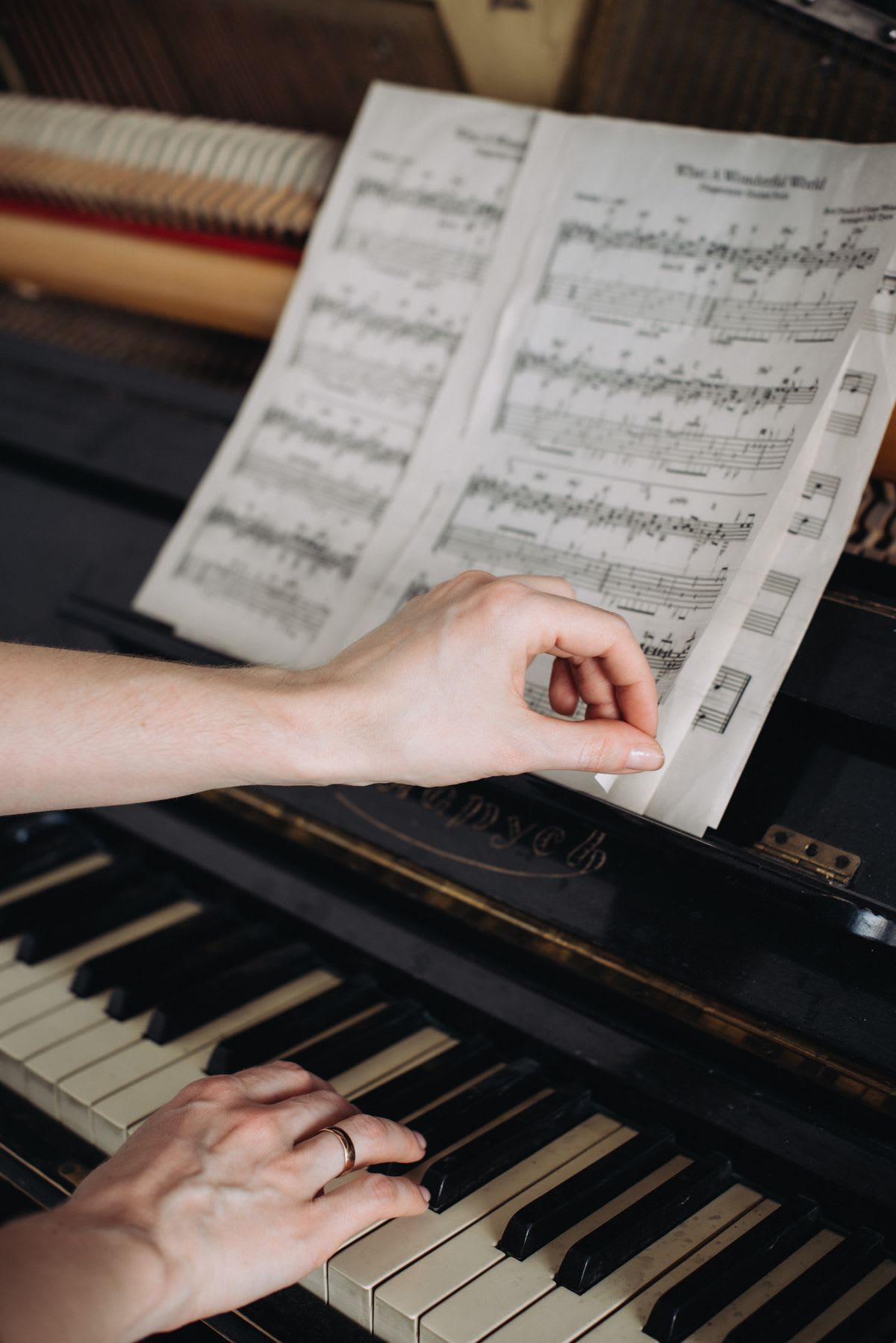 A pianist turns a printed score page while keeping one hand at the keyboard