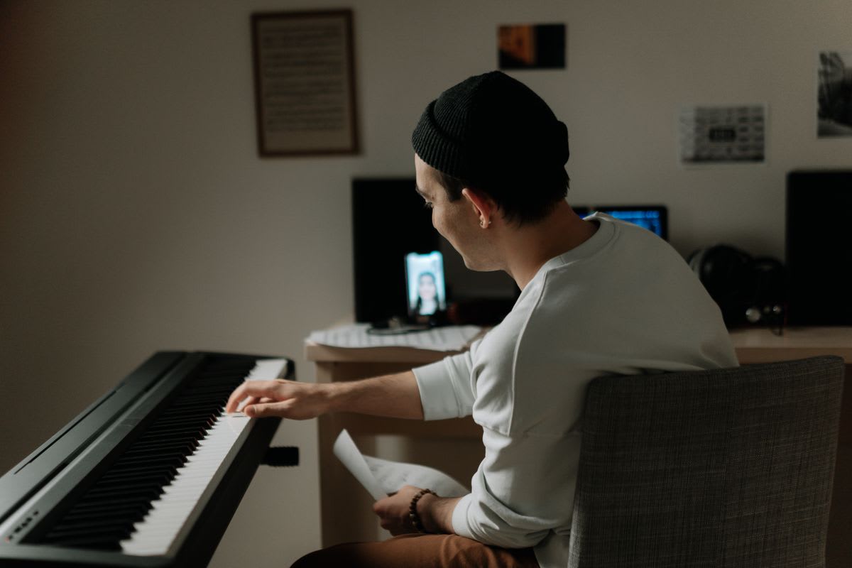 Adult pianist using sheet music while receiving guidance on a phone screen