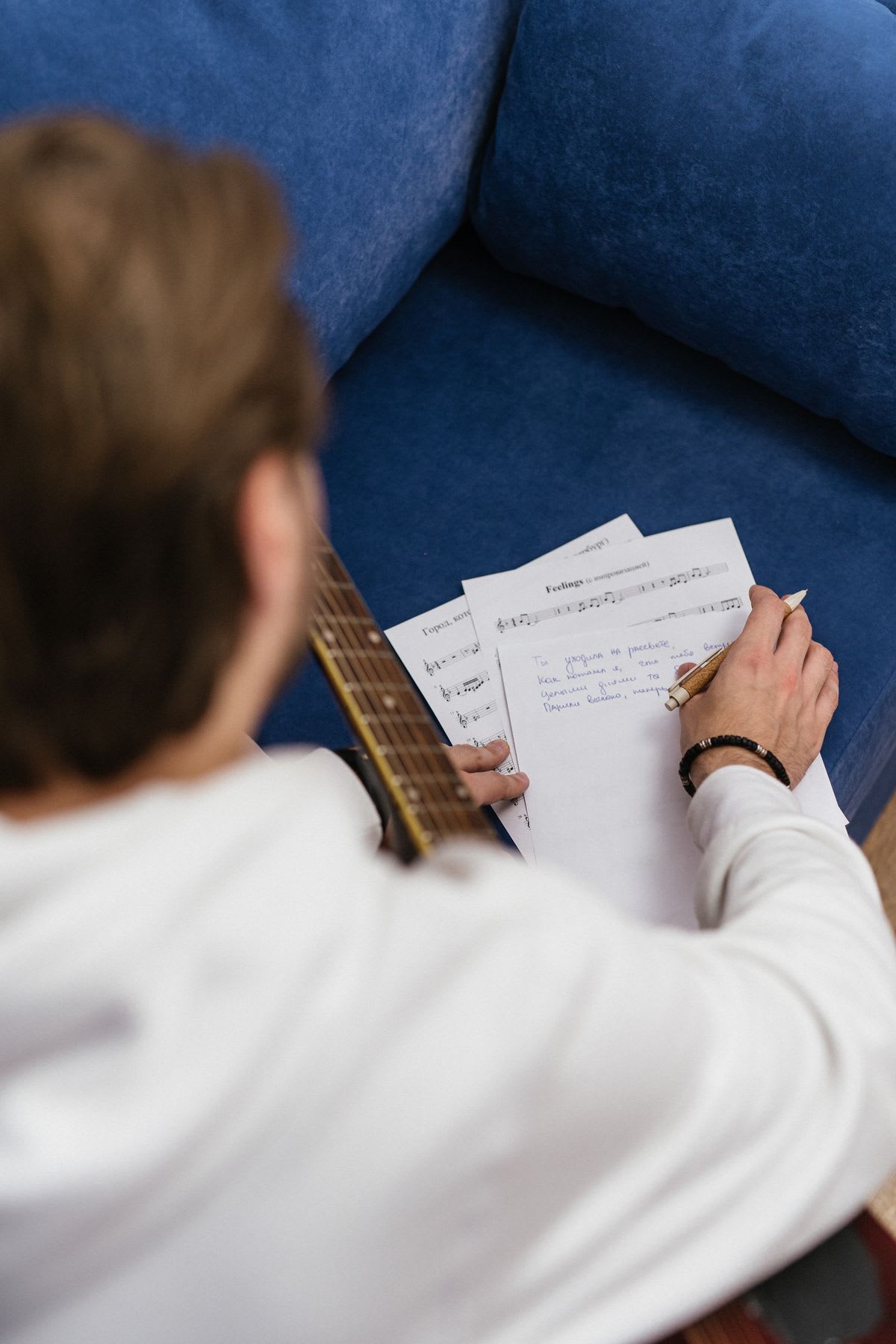Un guitariste écrit au crayon sur des feuilles de musique
