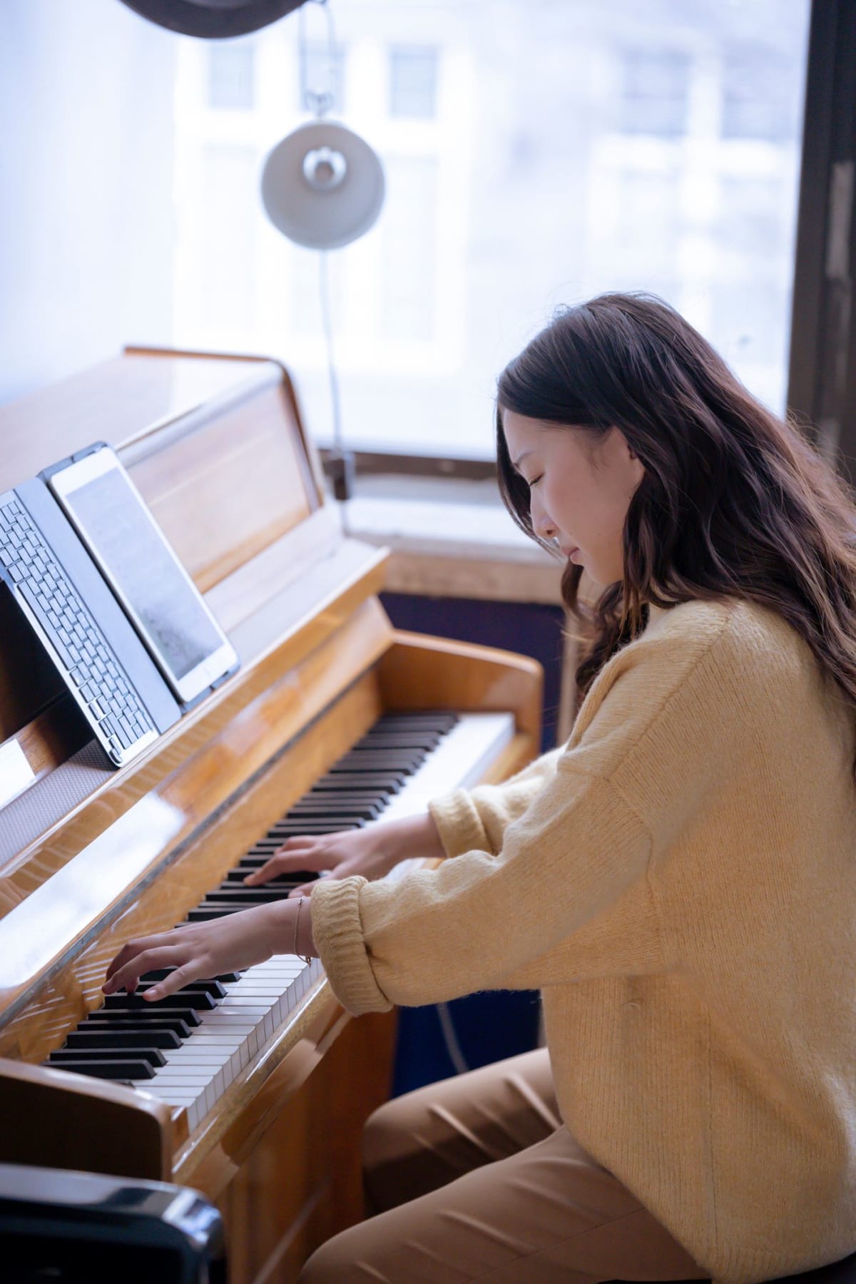 Pianista a estudar num piano vertical com um ecrã junto à partitura