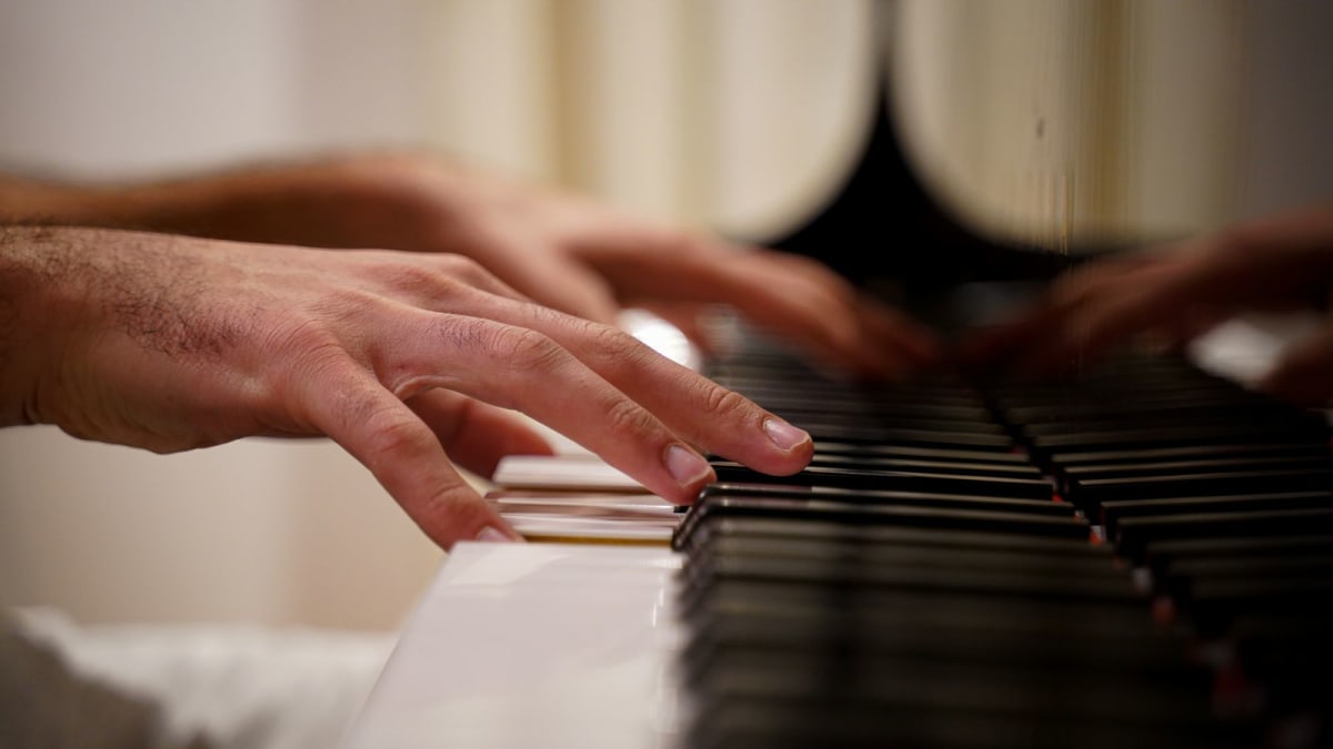 Pianist testing touch and control with both hands across piano keys
