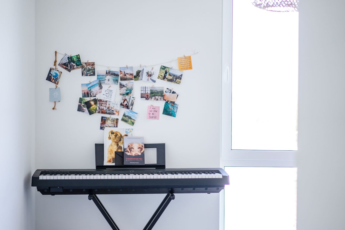 Full-size electronic keyboard set against a wall in a small bright practice corner