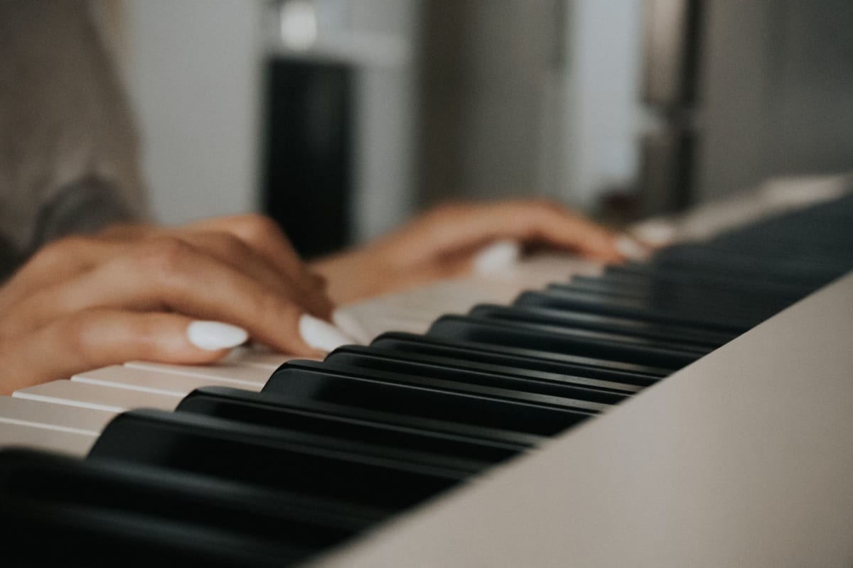 Close-up of a pianist’s hands testing full-size piano keys