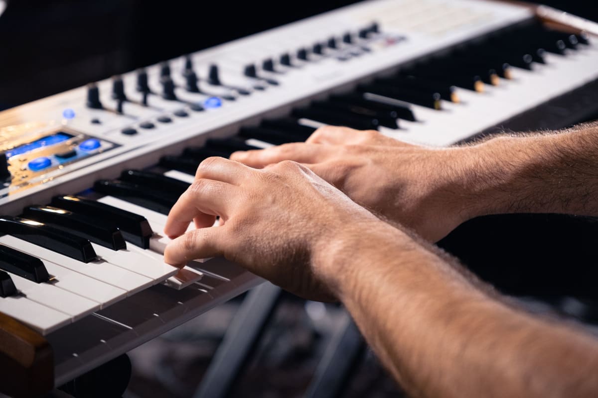 Hands testing the keys and controls of an electronic keyboard