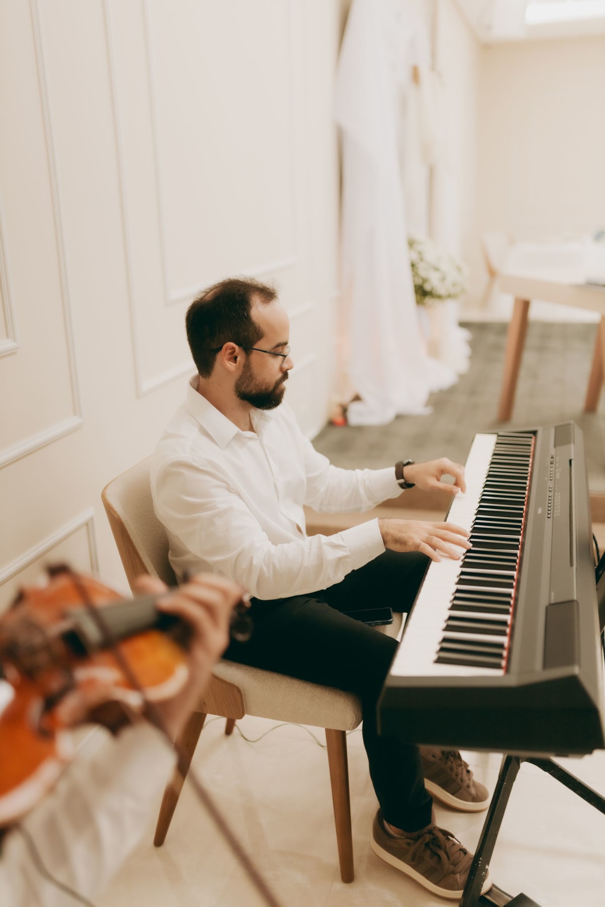 Pianist seated side-on at a digital piano showing chair and keyboard height